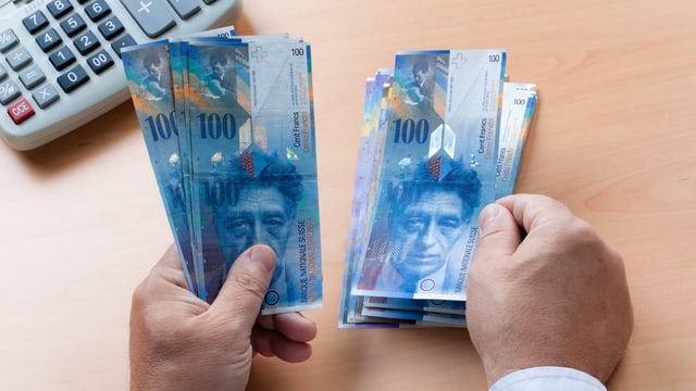 Mann legt 100er-Noten auf den Tisch Mann legt 100er-Noten auf den Tisch