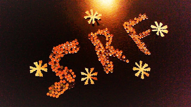 SRF 1-Logo aus weissen und orangen Rechaud-Kerzen.