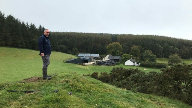 Wyn Evans auf einem kleinen Hügel mit Blick auf seinen Hof. Wyn Evans auf einem kleinen Hügel mit Blick auf seinen Hof.