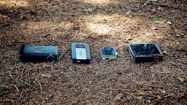 Vier Pico-Projektoren liegen am Waldboden.
