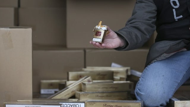 Ermittler hält Packung Zigaretten Ermittler hält Packung Zigaretten