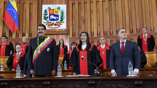 Maduro und weitere Personen stehen in einem Gerichtssaal. Maduro und weitere Personen stehen in einem Gerichtssaal.