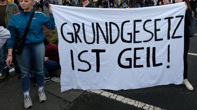 Eine junge blonde Frau an einer Demo mit einem Plakat, auf dem steht: Grundgesetz ist geil. Eine junge blonde Frau an einer Demo mit einem Plakat, auf dem steht: Grundgesetz ist geil.