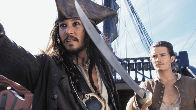 Johnny Depp und Orlando Bloom als Piraten auf einem alten Schiff.