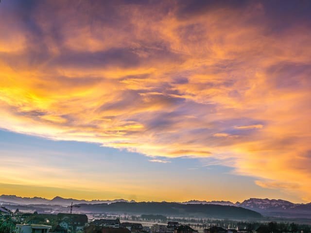 Blick über Mittelland mit farbigen Wolken am Himmel