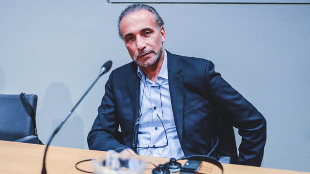 Ramadan sitzt an einem Tisch vor einem Mikrofon. Ramadan sitzt an einem Tisch vor einem Mikrofon.