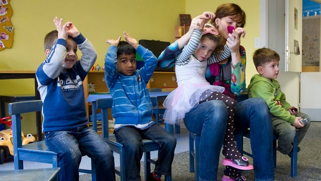 Vier Kinder spielen mit der Spielgruppenleiterin. Vier Kinder spielen mit der Spielgruppenleiterin.