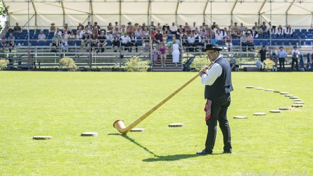 Ein Mann mit einem Instrument aus Holz das sehr lang ist. Ein Mann mit einem Instrument aus Holz das sehr lang ist.