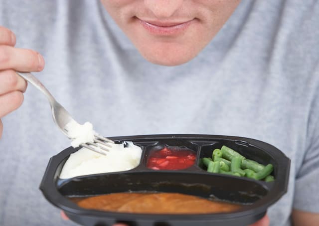 ein Mann isst Fertigsaucen aus einem Plastikgeschirr ein Mann isst Fertigsaucen aus einem Plastikgeschirr