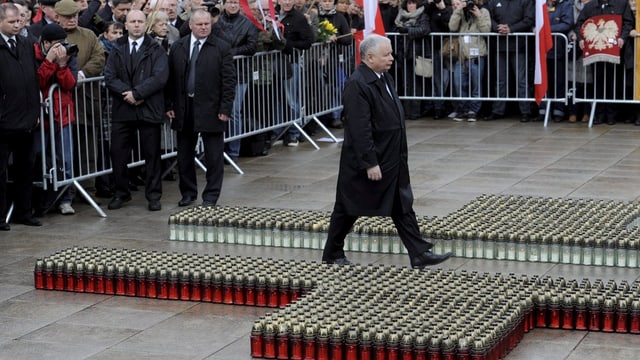 Jaroslaw Kaczynski schreitet durch ein Kreuz aus Grabkerzen zum Gedenkort seines Bruders. Jaroslaw Kaczynski schreitet durch ein Kreuz aus Grabkerzen zum Gedenkort seines Bruders.