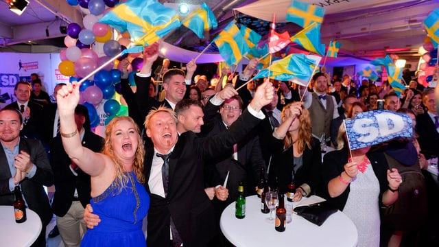 Jubelnde Parteimitglieder schwenken Schweden-Flaggen. Jubelnde Parteimitglieder schwenken Schweden-Flaggen.