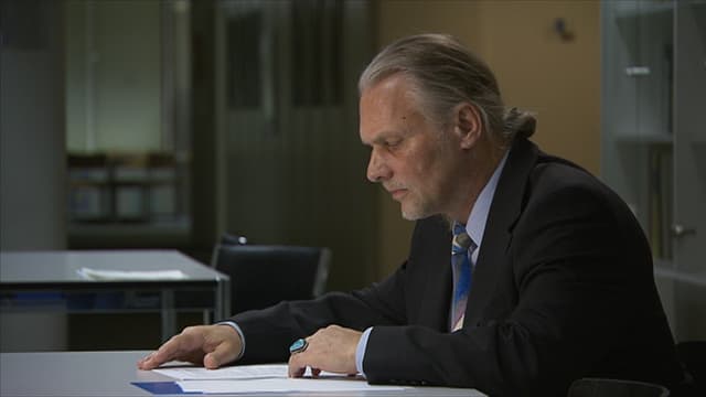 Mann an Tisch über Blättern Mann an Tisch über Blättern