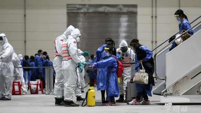 Am Flughafen führen Menschen in Schutzanzügen Coronatests bei Ankömmlingen durch. Am Flughafen führen Menschen in Schutzanzügen Coronatests bei Ankömmlingen durch.
