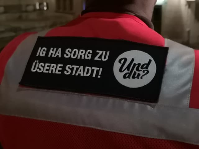 Leuchtweste mit Aufschrift «Ig ha Sorg zu üsere Stadt! Und du?» Leuchtweste mit Aufschrift «Ig ha Sorg zu üsere Stadt! Und du?»