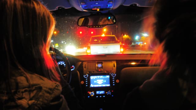 Zwei Frauen blicken im Dunkeln durch die Autoscheibe auf die dunkle Strasse. Zwei Frauen blicken im Dunkeln durch die Autoscheibe auf die dunkle Strasse.