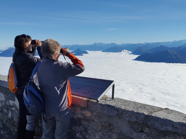 Zwei Frauen schauen mit Feldstechern übers Nebelmeer an die Berge. Zwei Frauen schauen mit Feldstechern übers Nebelmeer an die Berge.
