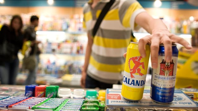 Ein junger Mann kauft zwei Dosen Bier Ein junger Mann kauft zwei Dosen Bier