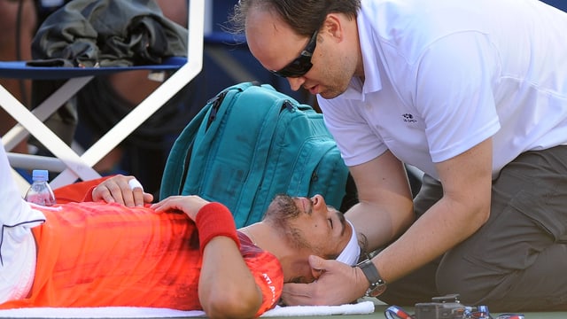 Fabio Fognini liegt am Boden und muss sich vom Physiotherapeuten am Rücken behandeln lassen. Fabio Fognini liegt am Boden und muss sich vom Physiotherapeuten am Rücken behandeln lassen.