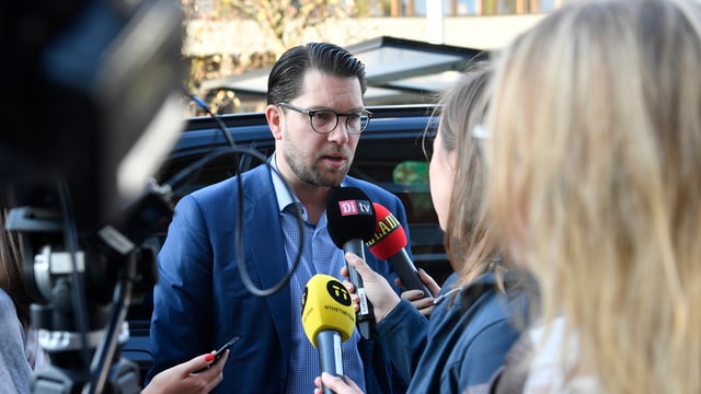 Mann gibt Journalistinnen ein Interview, Radiomikrofone vor seinem Gesicht. Mann gibt Journalistinnen ein Interview, Radiomikrofone vor seinem Gesicht.