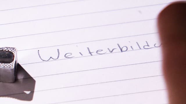 Das Wort Weiterbildung wird mit Bleistift auf Linienpapier geschrieben Das Wort Weiterbildung wird mit Bleistift auf Linienpapier geschrieben