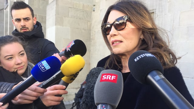 Frau mit Sonnenbrille hinter mehreren Mikrofonen Frau mit Sonnenbrille hinter mehreren Mikrofonen
