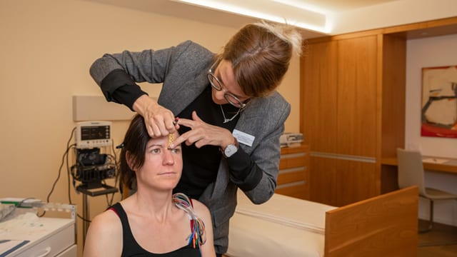 Eine Frau misst die Stirn einer anderen Frau. Eine Frau misst die Stirn einer anderen Frau.