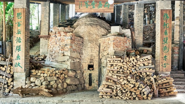 Der Drachenofen: ein rötlich-oranger Ofen mit Holz davorne. Der Drachenofen: ein rötlich-oranger Ofen mit Holz davorne.
