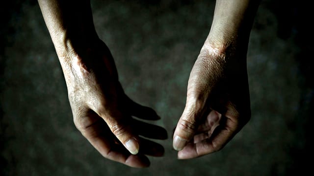 Hände einer Person, die offenbar kopfüber hängt. Hände einer Person, die offenbar kopfüber hängt.