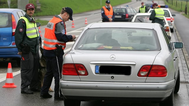 Grenzwächter und Polizisten in Leuchtwesten kontrollieren Autos. Grenzwächter und Polizisten in Leuchtwesten kontrollieren Autos.