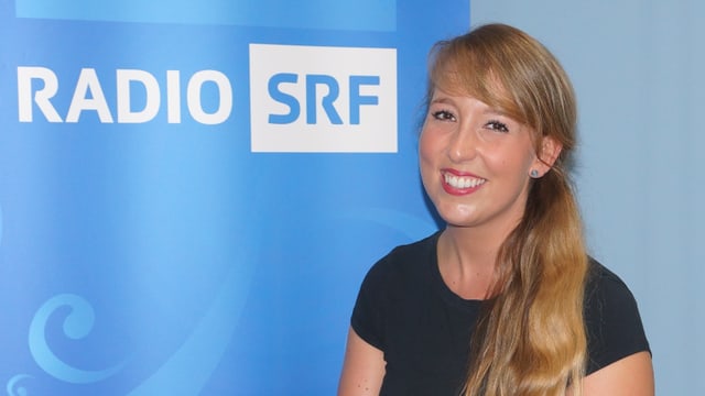 Junge Frau sitzt auf rotem Stuhl in schwarzem ärmellosen Shirt mit langem blonden Haar. Junge Frau sitzt auf rotem Stuhl in schwarzem ärmellosen Shirt mit langem blonden Haar.