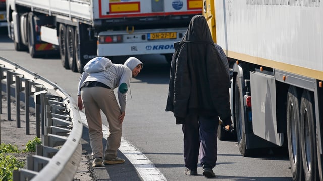 Ein Flüchtling schaut unter einen Lastwagen Ein Flüchtling schaut unter einen Lastwagen