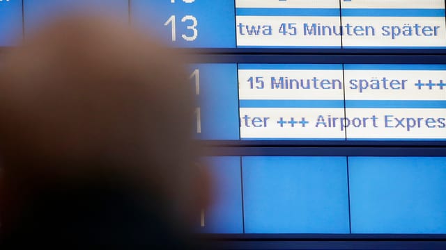 Bahnkunde steht vor einer Anzeigentafel. Bahnkunde steht vor einer Anzeigentafel.