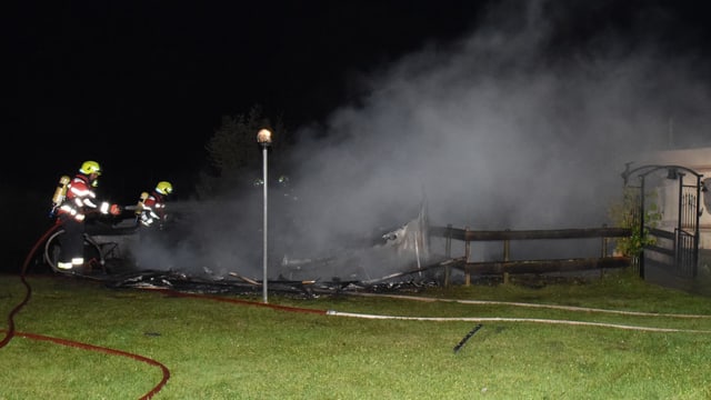 Feuerwehrleute bekämpfen einen Brand mit Wasserschläuchen im dichten Rauch. Feuerwehrleute bekämpfen einen Brand mit Wasserschläuchen im dichten Rauch.