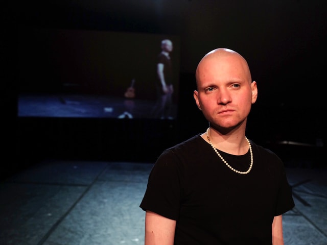 Julian Meding mit Glatze, schwarzem T-Shirt und Perlenkette Julian Meding mit Glatze, schwarzem T-Shirt und Perlenkette