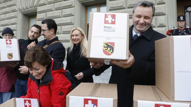 Werner Salzmann und weitere Menschen bringen die Unterschriften in grossen Kartonboxen vors Bundeshaus. Werner Salzmann und weitere Menschen bringen die Unterschriften in grossen Kartonboxen vors Bundeshaus.