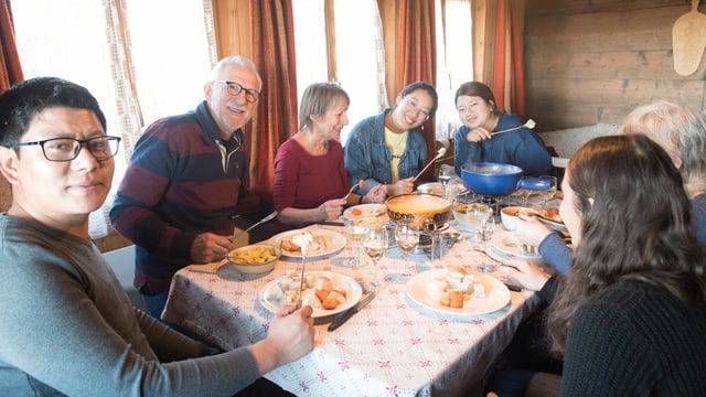 Menschen, die an einem Tisch Fondue essen. Menschen, die an einem Tisch Fondue essen.