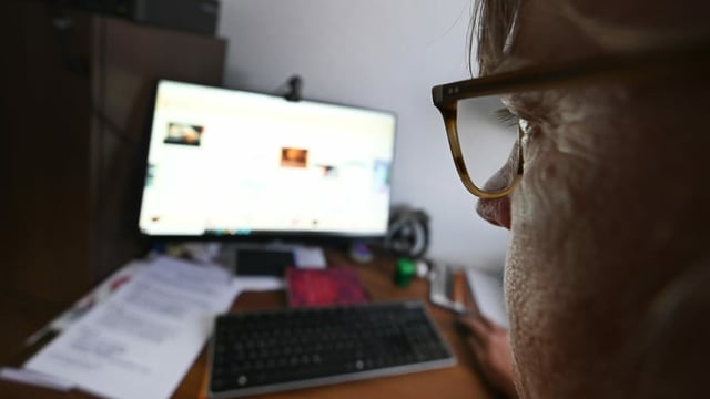 Mann mit Brille sitzt vor Computer Mann mit Brille sitzt vor Computer