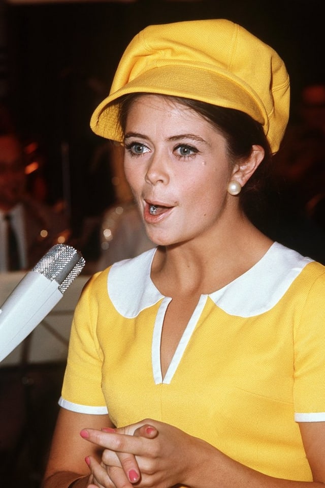 Star singt in Microphon in gelbem Outfit miit keckem Hut. Star singt in Microphon in gelbem Outfit miit keckem Hut.