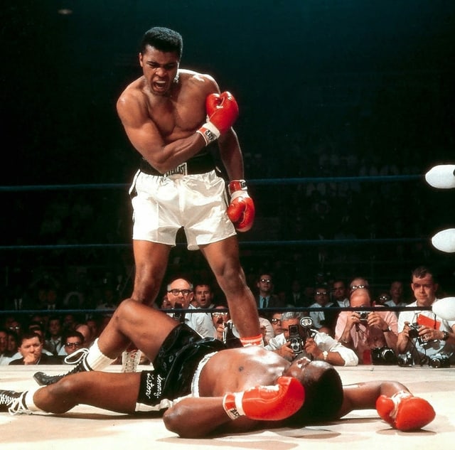 Ali brüllt den am Boden liegenden Liston an. Ali brüllt den am Boden liegenden Liston an.