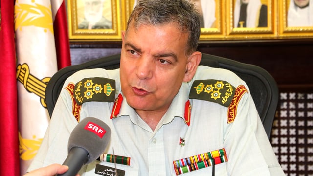 Brigadier-General Saad Jaber in einem Büro. Mit im Bild das Mikrofon von SRF Auslandkorrespondentin Susanne Brunner. Brigadier-General Saad Jaber in einem Büro. Mit im Bild das Mikrofon von SRF Auslandkorrespondentin Susanne Brunner.