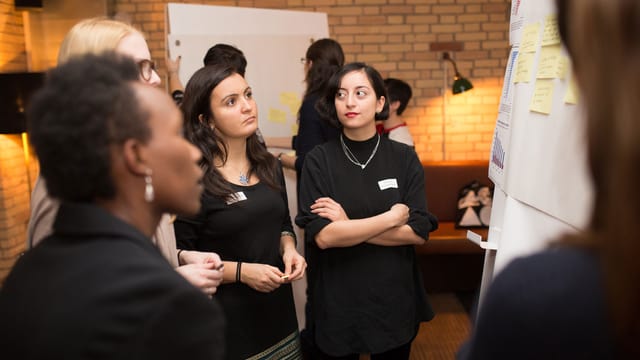 Vier Frauen stehen um ein Flip Chart und diskutieren. Vier Frauen stehen um ein Flip Chart und diskutieren.