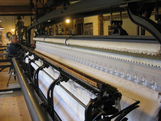 Hollenstein sitzt an seiner grossen Maschine und stickt ein Blumenmotiv. Hollenstein sitzt an seiner grossen Maschine und stickt ein Blumenmotiv.