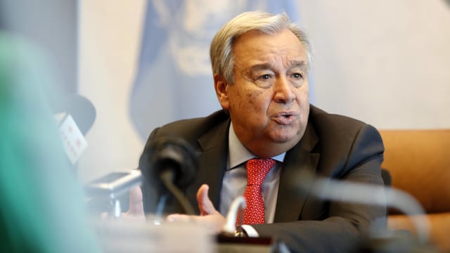 Guterres sitzt vor einer UNO-Flagge an einem Tisch und spricht in ein Mikrofon. Guterres sitzt vor einer UNO-Flagge an einem Tisch und spricht in ein Mikrofon.