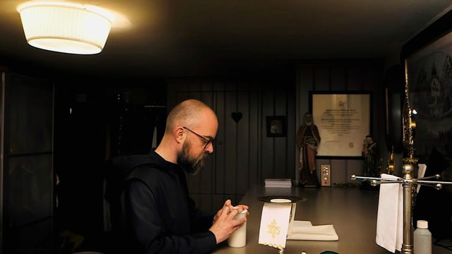 Ein Mönch betet an einem Tisch. Ein Mönch betet an einem Tisch.