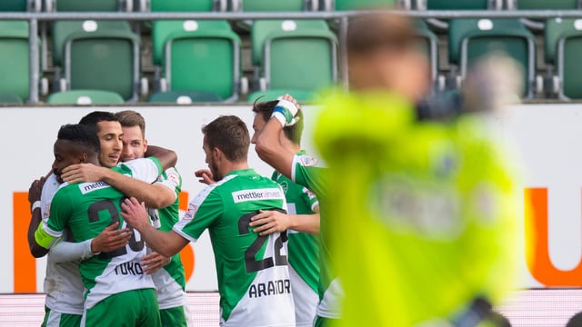 Fussballer umarmen sich im Hintergrund, unscharf im Vordergrund der besiegte Torhüter. Fussballer umarmen sich im Hintergrund, unscharf im Vordergrund der besiegte Torhüter.