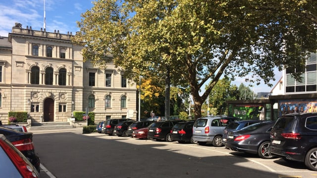 Ein Gebäude aus Stein, davor ein Parkplatz. Ein Gebäude aus Stein, davor ein Parkplatz.