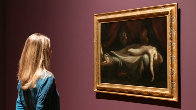 Eine Frau begutachtet ein Kunstwerk im Museum Eine Frau begutachtet ein Kunstwerk im Museum