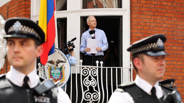 Assange spricht von Balkon aus zu Medien, davor britische Polizisten