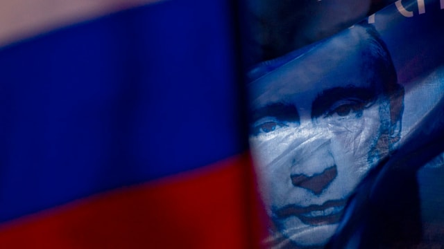 Putins Gesicht hinter russischer Flagge Putins Gesicht hinter russischer Flagge