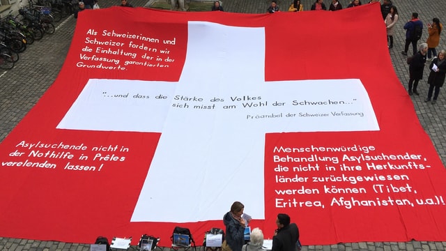 Ein grosses Schweizerkreuz mit Forderungen drauf. Ein grosses Schweizerkreuz mit Forderungen drauf.
